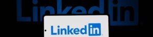 Smartphone showing LinkedIn logo with keyboard and large background logo, business theme.